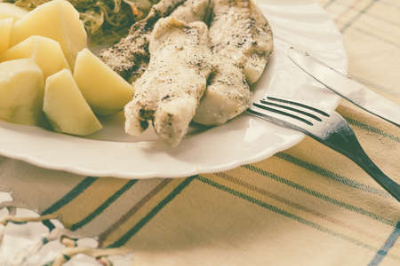 Food. Ready delicious dinner fish meat with salad and potatoes on kitchen home table. Meal time. Indoor.の写真素材