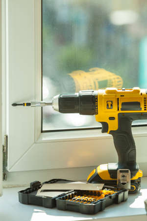 Driller with drill bits standing on windowsill. Renovation, building things object tools.の写真素材