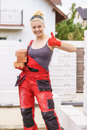 Strong pretty woman working on construction site, building house, installing bricks. Industrial work concept.の写真素材