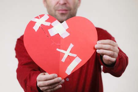 Bad relationships, breaking up, sadness emotions concept. Adult man holding broken heart, on greyの写真素材