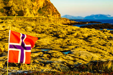 Norwegian flag waving on wind against sea coast on Andoya island near Nordmela village Vesteralen archipelago, Norway.の写真素材
