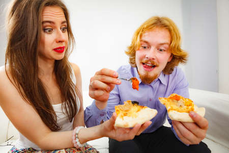 Man and woman spending time together. Couple or friends eating delicious cheesy pizza.の写真素材