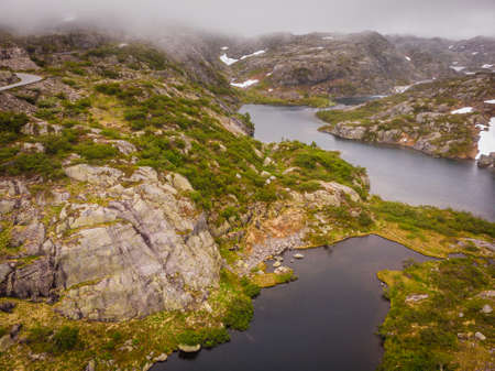 Lakes in stone rocky mountains, misty foggy day. Norway summer landscape. Norwegian national tourist...