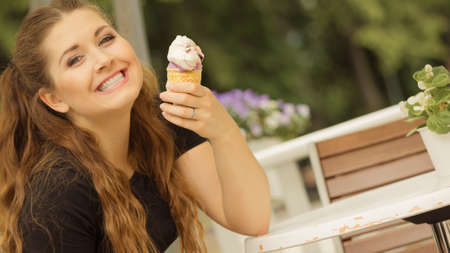 Happy funny young woman with long brown hair eating ice cream having fun.