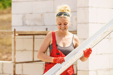 Woman carrying steel metal made gutter on her house construction site, building new home, fixing hydraulicsの写真素材