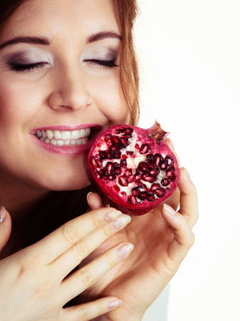 Woman cheerful brunette girl holding pomegranate fruits in hands on white. Healthy eating, cancer prevention, immune support.の写真素材