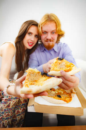 Funny crazy man and woman spending time together. Cheerful couple or friends eating delicious cheesy pizza.の写真素材