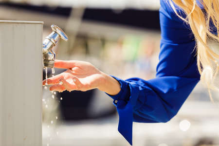 Woman cleaning washing her hands outdoor in marine water dispenser. Hygiene concept.の写真素材