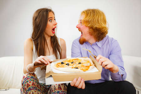 Man and woman spending time together. Couple or friends eating delicious cheesy pizza.の写真素材