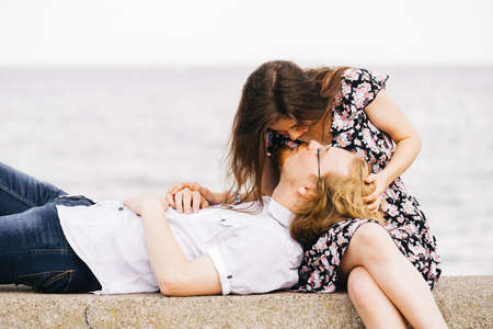 Man lying on woman legs enjoying their romantic date near coastline and water seaside.の写真素材