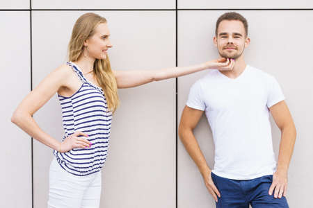 Date and love concept. Blonde young woman touching tender her boyfriend outdoors.