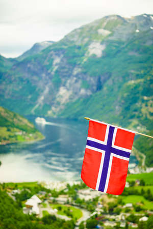 Norwegian flag and view over Geirangerfjord from Flydalsjuvet viewing point. Tourist attraction. Tourism vacation and travel.の写真素材