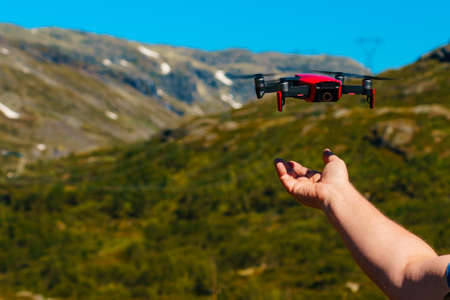 Start the drone, launching from hands. Modern small copter with camera in user hand, against nature. Technological equipment.の写真素材