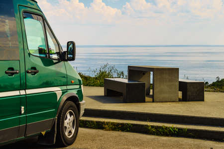 Camper car on rest stop area, viewpoint with stone seating bench on sea ocean shore. Attractions...