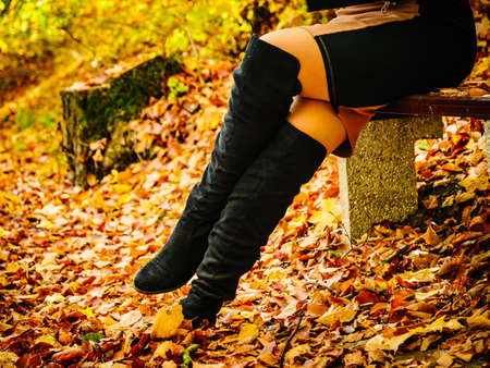 Woman wearing long black heeled knee high boots and jeans. Autumn fashion, warm footwear boots.