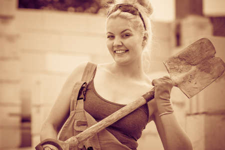 Woman worker using shovel standing on industrial construction site, working hard on house renovation.の写真素材