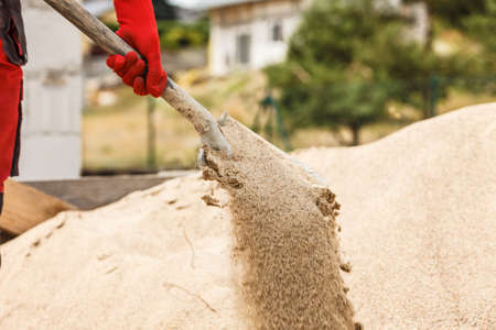 Unrecognizable person worker using shovel standing on industrial construction site, working hard on house renovation.の写真素材