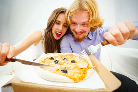 Funny crazy man and woman spending time together. Cheerful couple or friends eating delicious cheesy...