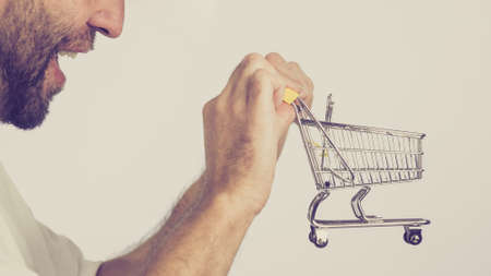 Man holding empty shopping basket cart, toned image. Seasonal sales, boxing day concept.の写真素材