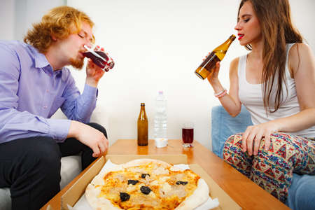 Young couple of friends spending time together drinking beer and eating italian food, delicious...