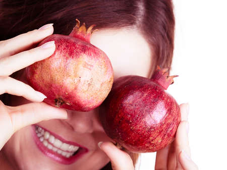 Joyful young woman playing with pomegranate fruits, isolated on white. Healthy eating, cancer prevention, immune support concept.の写真素材