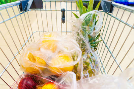 View from shopping cart trolley basket at supermarket self service grocery shop. Fruits and...