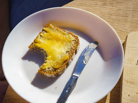 Preparing breakfast meal. Rye bread slice with butter and honey on white plate.の写真素材