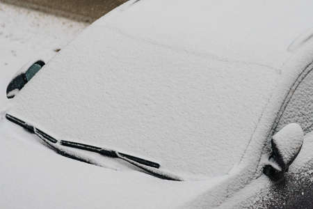 Winter season and seasonal specific. Car parked on city street covered in snowの写真素材