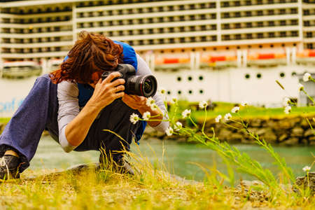Woman with camera take travel photo. Cruise ship on fjord Aurlandsfjord in norwegian tourist destination Flam village in distanceの写真素材