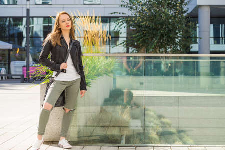 Woman walking around modern city wearing black jeans jacket. Female fashion model during spring weather.の写真素材