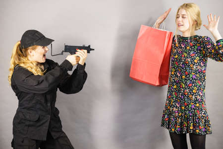 Shoplifting is a crime. Young fashionable woman being caught on stealing clothes by female security guard. Customer being thief.の写真素材