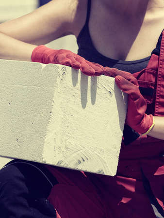 Unrecognizable woman working on construction site, building house, installing gray airbricks. Industrial work concept.の写真素材