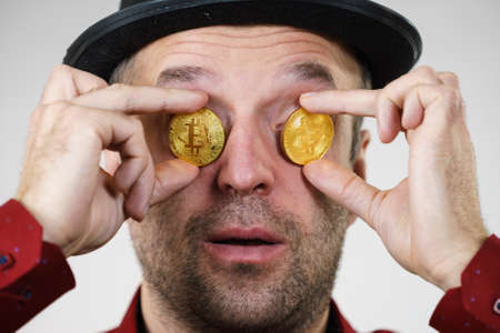 Adult man having bitcoin coin as pince nez in eye. Crypto internet currency banking concept.