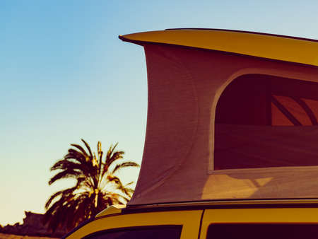Camper van with tent on roof camping on mediterranean coast with palm trees in Spain. Holidays and travel in motor home.の写真素材