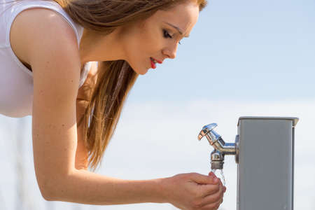 Woman drinking clean water from street tapの写真素材