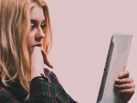 Young teenage woman using tablet surfing on internet, working or getting inspirations.の写真素材