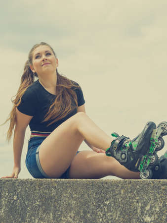 Young woman wearing roller skates outdoor. Fashionable fit girl having fun resting at sunny summer day.の写真素材
