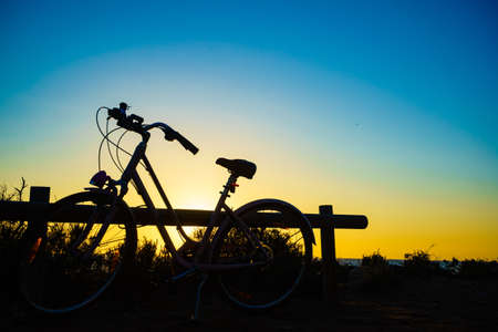 Bicycle outdoor parked on beach, evening time, sunset sky. Holidays, sport and recreation.の写真素材