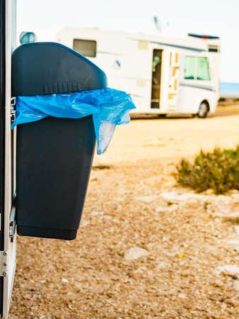 Camper, recreational vehicle outdoor on nature and trash can with plastic bag inside. Camping on seaside. Holidays and travel in caravan.の写真素材
