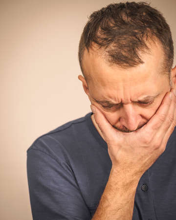 Depressed, sad, worried adult man covering his mouth feeling guilt and shame.