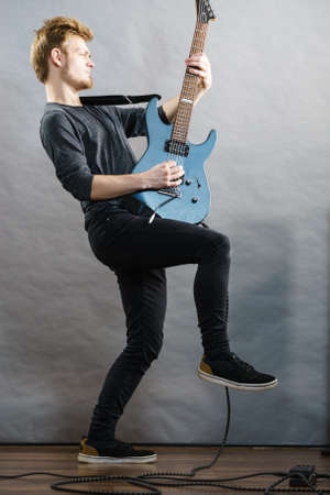 Man being passionate about his music hobby, playing electric guitar emotionally.