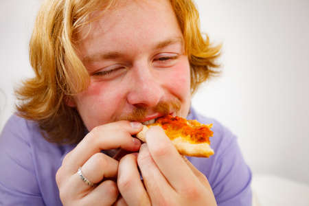 People, italian cuisine concept. Young bearded man eating hot fresh pizza. Delicious fast food meal.