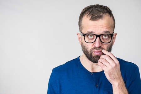 Adult clever guy wearing eyeglasses and blue shirt having thinking, focused face expression. Man focusing on his work, contemplating idea.の写真素材
