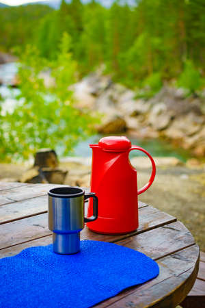 Picnic site table with flask and thermal mug, norwegian mountains nature in the background.の写真素材