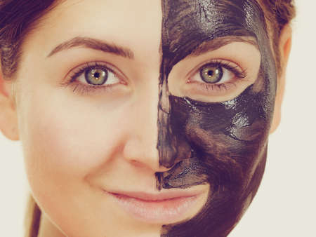 Woman with clay carbo detox black mask on her face. Girl taking care of oily skin complexion. Beauty treatment. Skincare.の写真素材