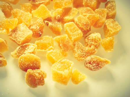 Heap of crystallized candied ginger pieses on white plate. Yummy snack, better alternative to candy.の写真素材
