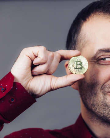Man holding golden bitcoin coin sign, digital symbol of new virtual currency