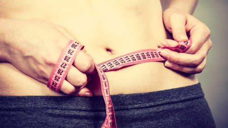 Getting rid of belly fat, diet, weight loss or gain concept. Woman touching stomach holding...
