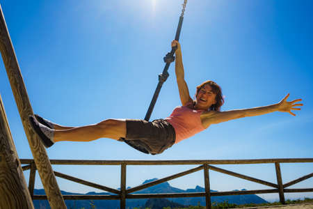 Adult freedom woman tourist having fun on zipline, descend on rope, cable aerial ropeslide. Mountains rest place in Spain Alicante region. Costa Blanca holiday.の写真素材