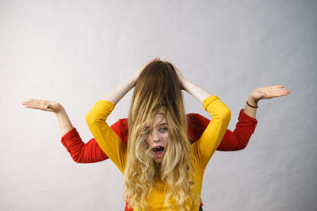 Woman playing with her female friend long ombre color hair. Different hairdo colors, haircare and...
